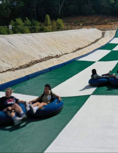 Snowless tubing hill with people on summer tubes.