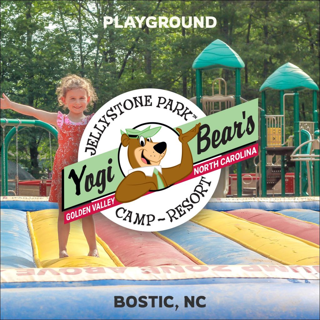 Kid on jumping pillow in front of playground at Yogi Bear campground near Charlotte, NC.