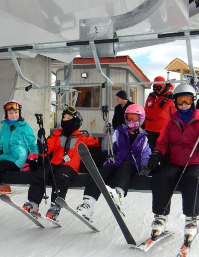 People with snow skiis on chairlift at Sugar Mountain resort.