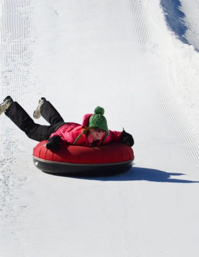 Person riding snow tube down snow tubing hill.