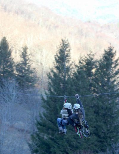 People on tandem zipline with mountains in background at ziplining location near Hickory, NC.