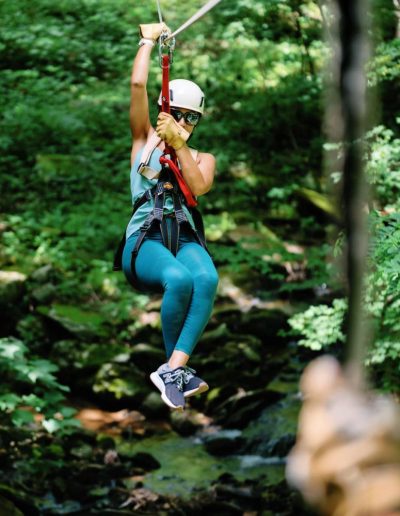 Woman ziplining through the woods at Hawksnest near Boone, NC.