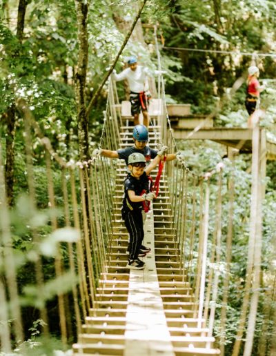 Kid on rope bridge between zipline stops at zipline attraction in NC mountains.