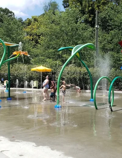 Children playing among colorful water features at the Burlington City Park splash pad.