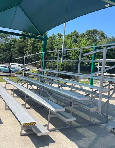 Shaded bleachers beside the sports courts at Burlington City Park.