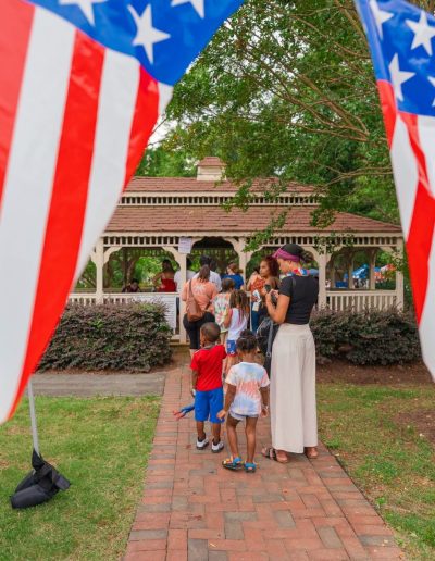 Families gathered near a gazebo decorated with patriotic bunting at Burlington City Park.