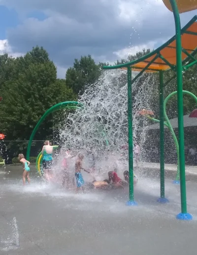 Children beneath a cascading water feature at Burlington Splash Park.
