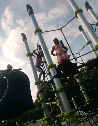 Children climbing a rope playground structure at Burlington City Park.