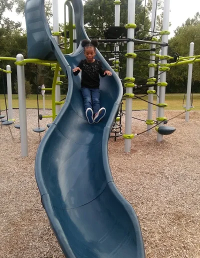 Child sliding down playground equipment at Burlington City Park.