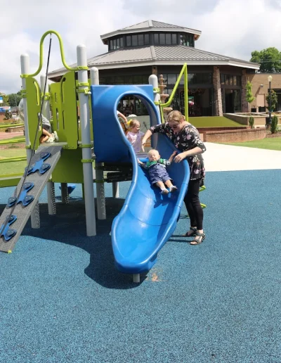 Toddler sliding with help from an adult at Burlington City Park.