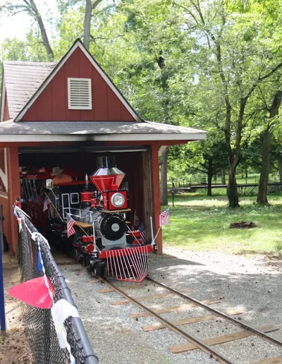 Red miniature train at the Burlington City Park amusement area depot.