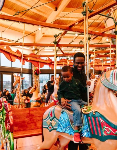 Child riding a painted carousel horse at Burlington City Park.