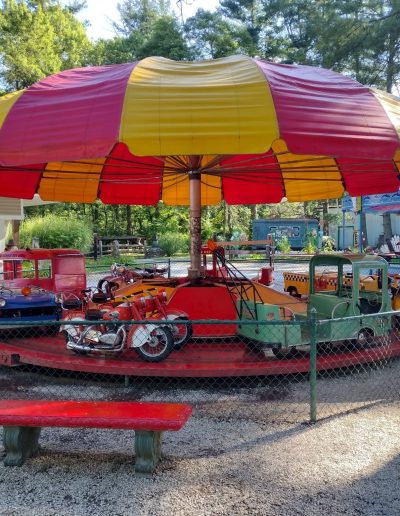 Colorful children’s vehicle ride beneath striped canopy at Santa’s Land in Cherokee, NC