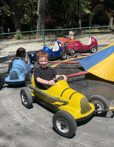 Child driving a yellow car on a children’s ride at Santa’s Land in Cherokee, NC