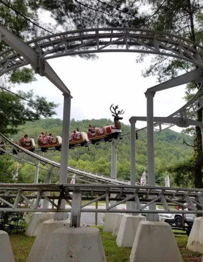 Rudicoaster train traveling along elevated track through trees at Santa’s Land in Cherokee, NC