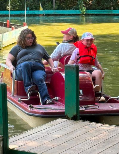 Family seated in a red pedal boat beside a dock at Santa’s Land in Cherokee, NC