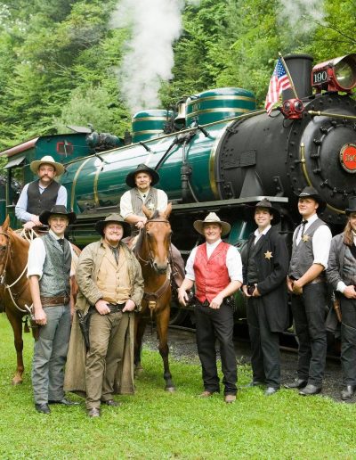 Wild West cast posing with Tweetsie Railroad steam locomotive