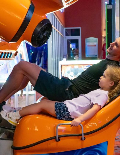 Adult and child on a yellow arcade simulator at Frankie's of Charlotte in Huntersville, NC.