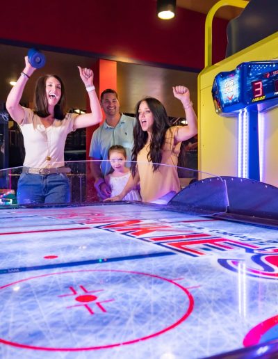 Friends celebrating around an air hockey table at Frankie's of Charlotte in Huntersville, near Belmont.