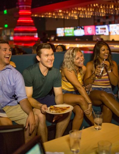 Friends sharing pizza in a lounge seating area at Frankie's of Charlotte in Huntersville, NC.