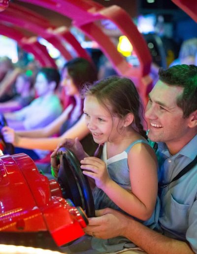 Adult and child steering an arcade racing game at Frankie's of Charlotte in Huntersville, near Davidson.