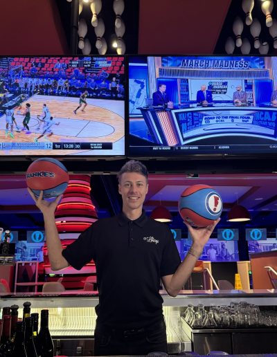 Staff member holding basketballs beside the bar at Frankie's of Charlotte in Huntersville, NC.