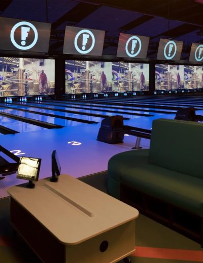 Blue-lit bowling lanes and lounge seating at Frankie's of Charlotte in Huntersville, NC.