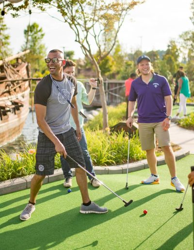 Mini-golf players smiling beside a pirate ship at Frankie's of Charlotte in Huntersville, NC.