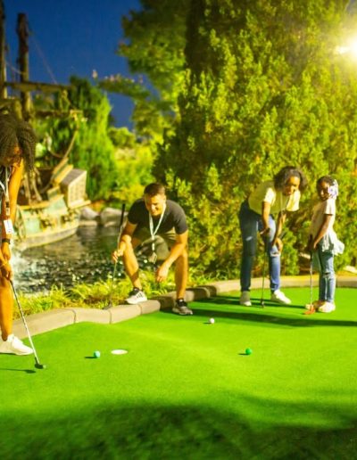 Friends playing mini golf under evening lights at Frankie's of Charlotte in Huntersville, NC.